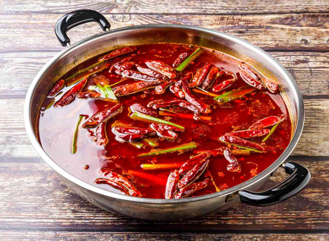  Spicy Sichuan hotpot with chili peppers and scallions served in steel pot